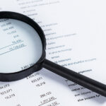 Magnifying glass on financial statement paper. Analyzing busines